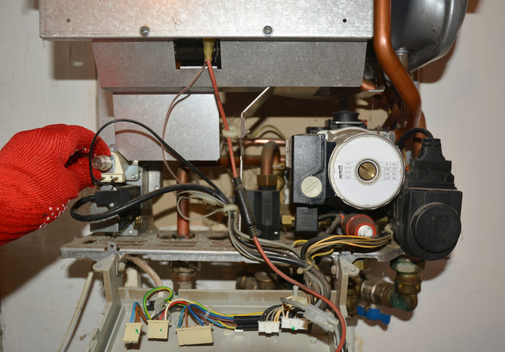 Technician wearing red gloves repairing a gas boiler